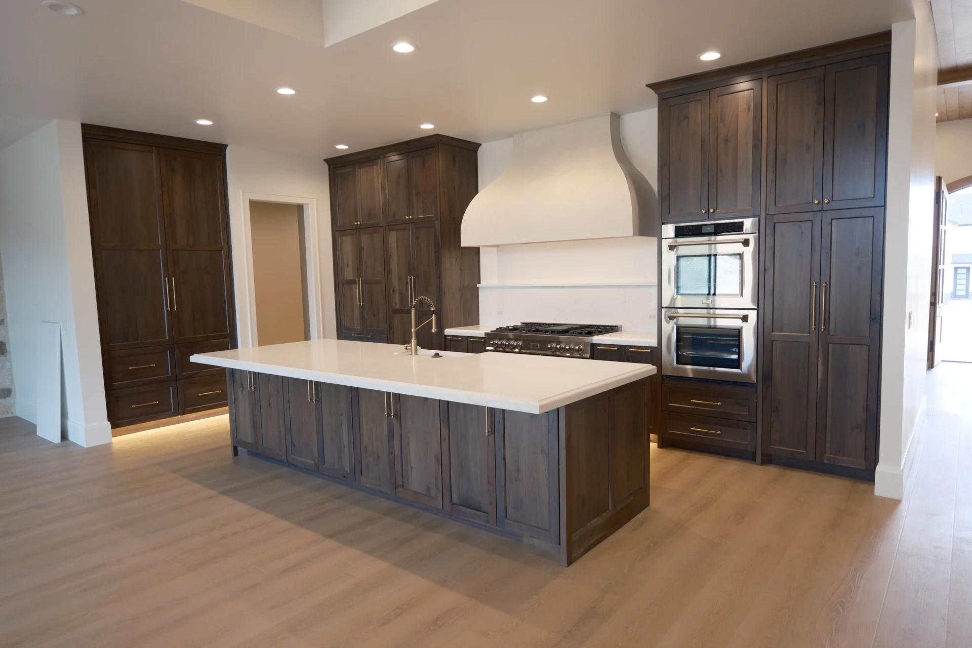 Two tone kitchen cabinets with dark stained wood island and white range hood, custom built by Rivermill in Hyde Park for a Cache Valley home